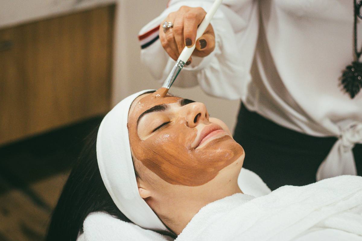 Woman applying smooth hair styling product with relaxed hair close-up